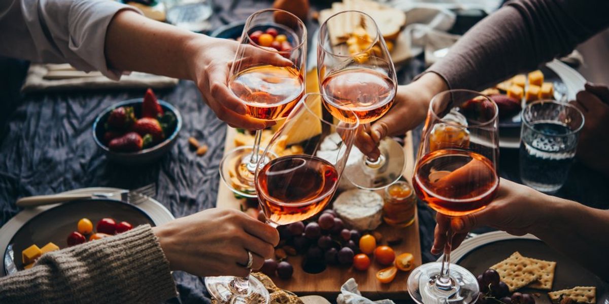 rosé borral koccint egy társaság, az asztalon sajt, kenyér, olíva bogyó, paradicsom