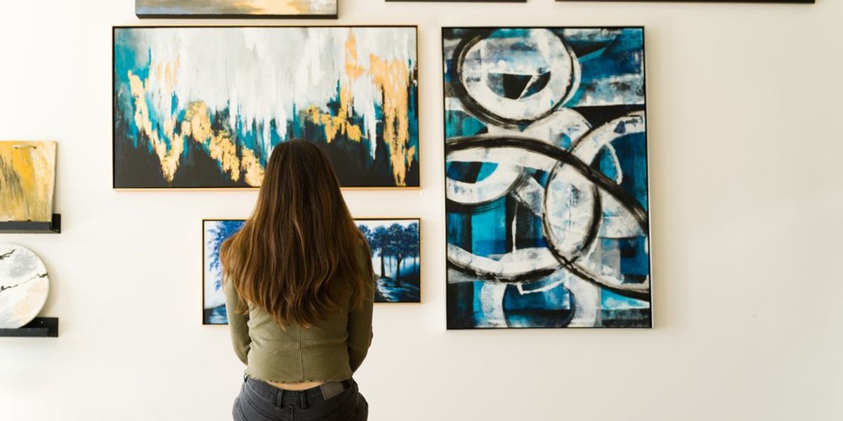 egy nő nézi a festményeket a falon