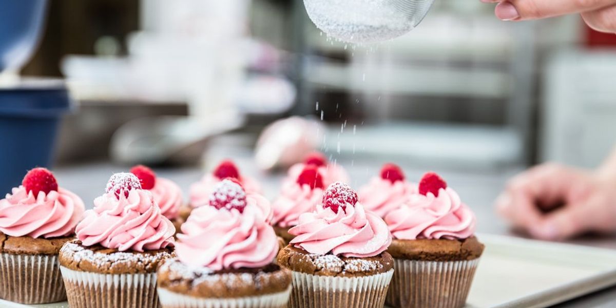 Málnás cupcake-et cukorral megszóró kéz