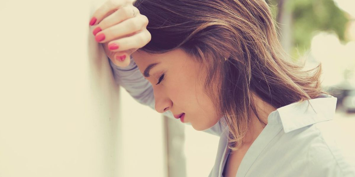 egy fiatal nő a stressz miatt a falnak dönti a homlokát