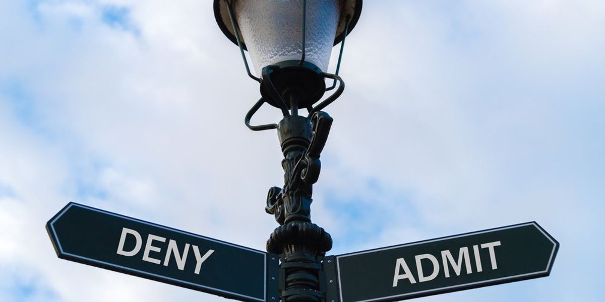 Utcai lámpaoszlop, két ellentétes irányú nyíllal, melyeken a tagadás és beismerés szavak állnak