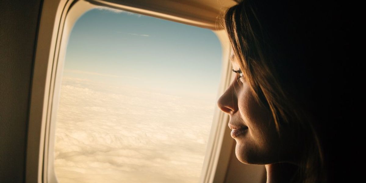 ablak mellett ül egy nő a repülőn