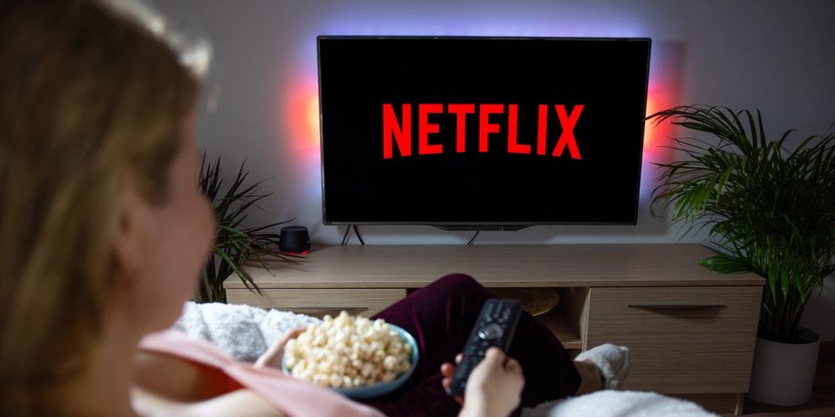 Fiatal nő popcornnal a kezében a Netflixet nézi