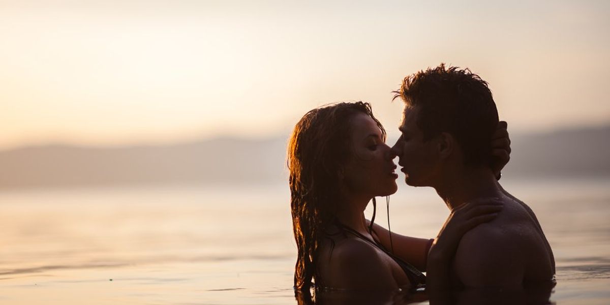 egy vízben, naplementében csókolózó pár