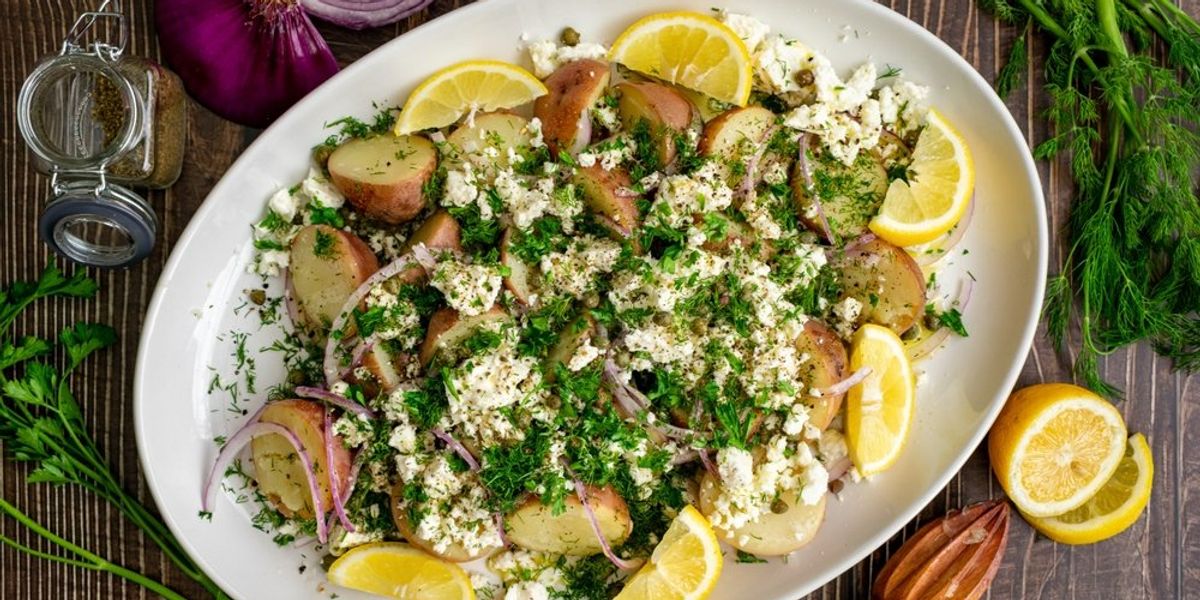 Görög burgonyasaláta fetasajttal, friss fűszernövényekkel és citromszeletekkel