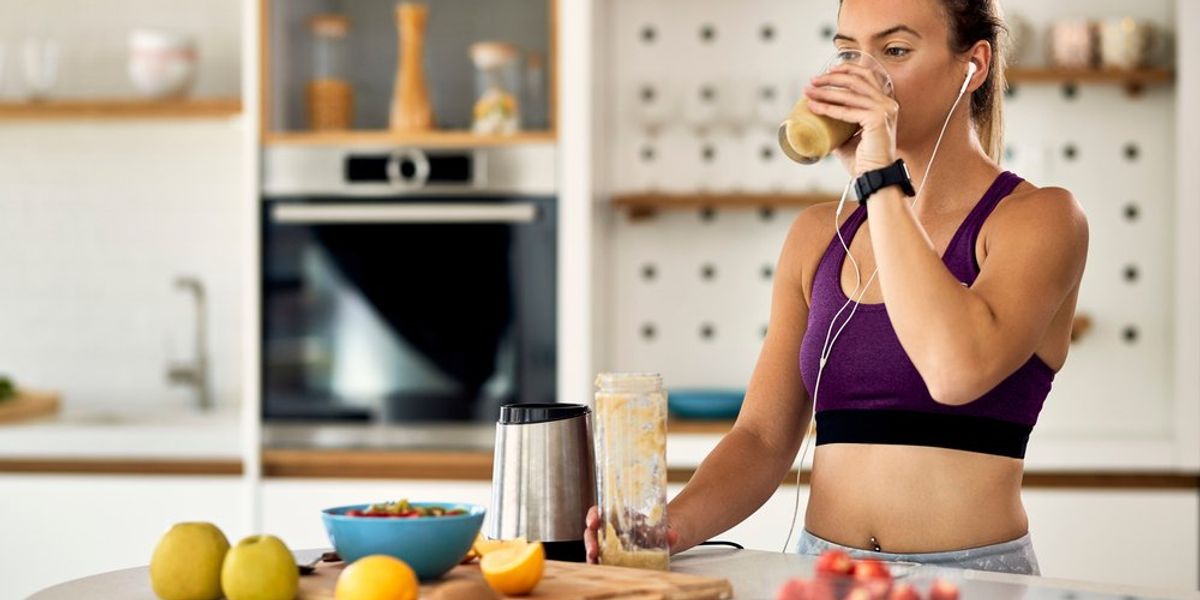Fiatal sportoló nő gyümölcs turmixot iszik edzés előtt