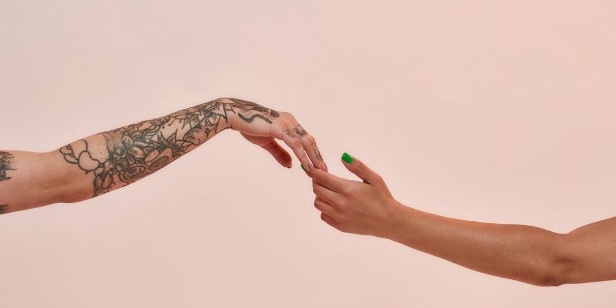 Egy tetovált és egy nem tetovált kéz fogja egymást