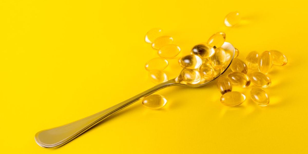 D-vitaminok egy kanálon és mellette, sárga háttéren