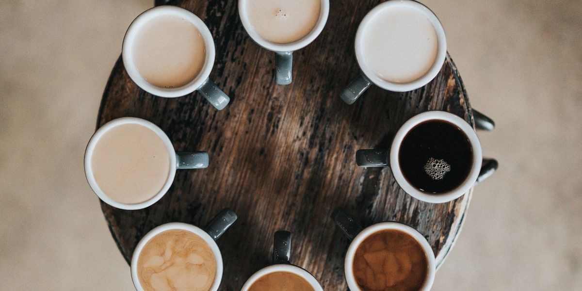 Különböző kávéitalok csészékben, kör alakban egymás mellett faasztalon