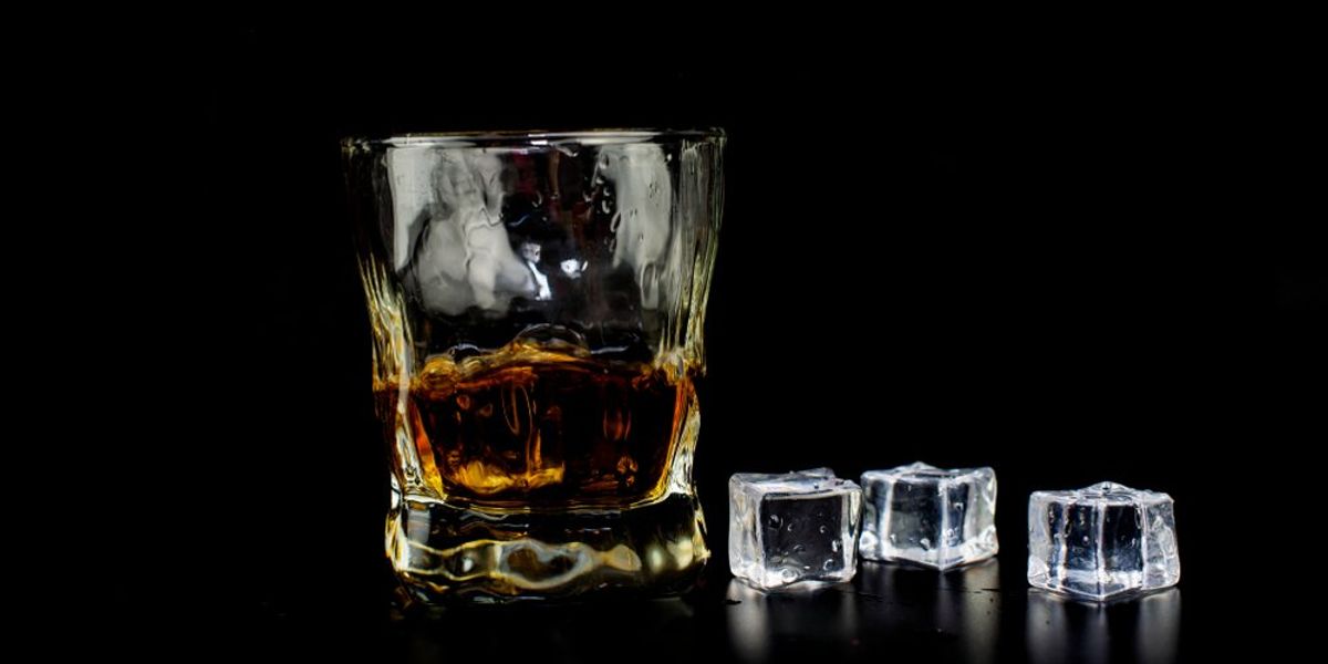 Pohár whiskey jégkockákkal fekete háttéren