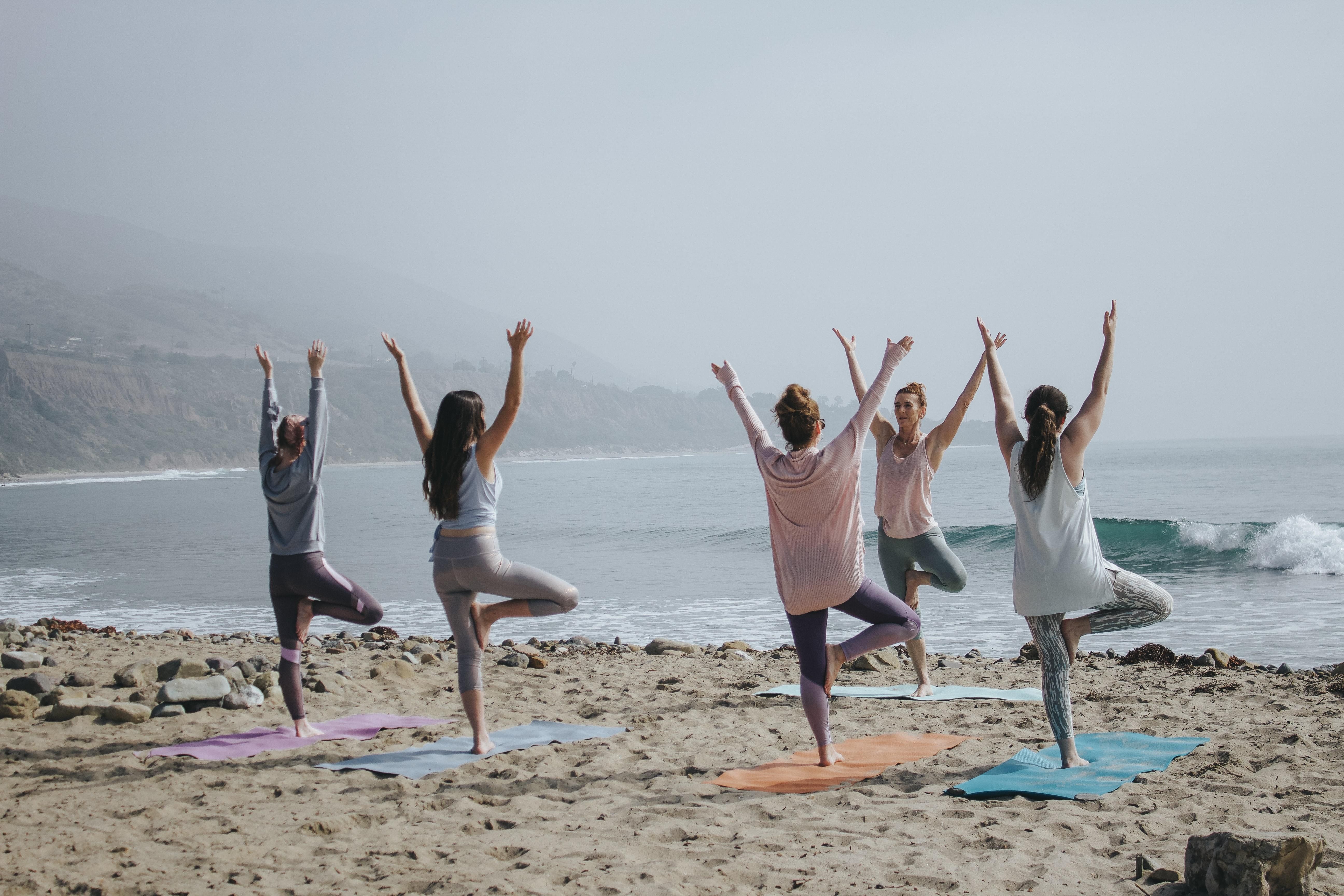 Nők együtt jógáznak a strandon