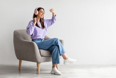 Fiatal nő fotelben ül és zenét hallgat