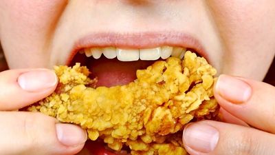 egy nő gyorsétkezdés sült csirkét eszik