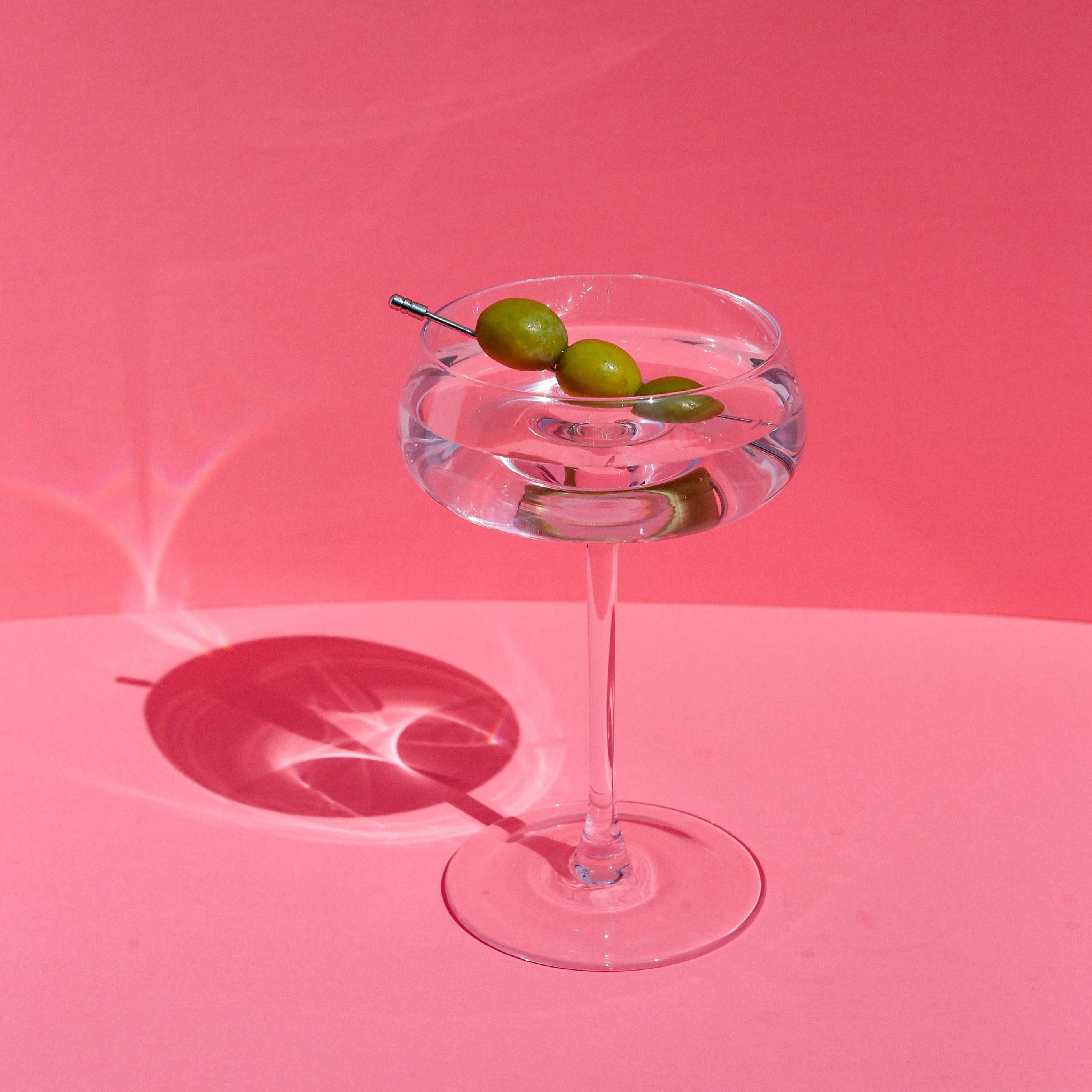 Egy pohár martini rózsaszín háttér előtt