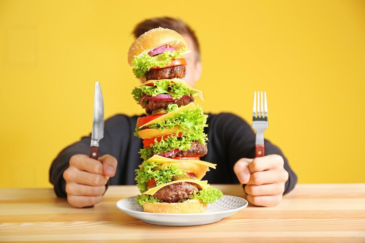Hatalmas hamburgert evő ember