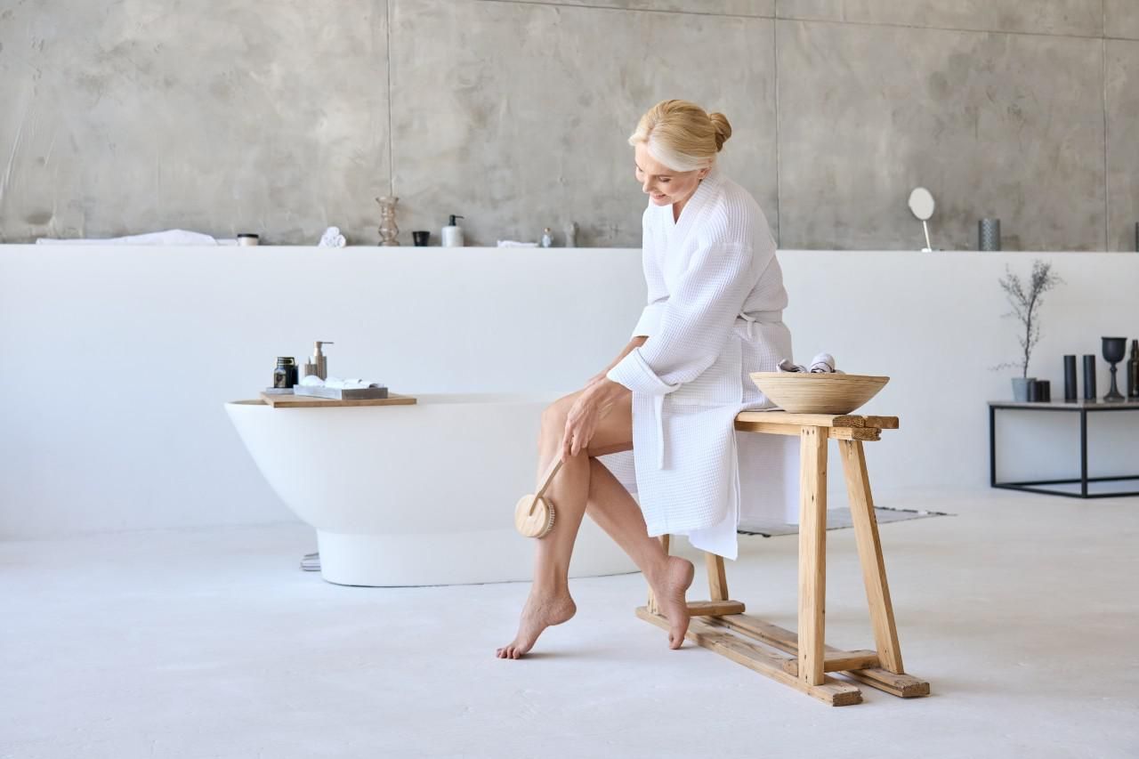 Fürdőköpenyben ülő nő  a bőrét ápolja