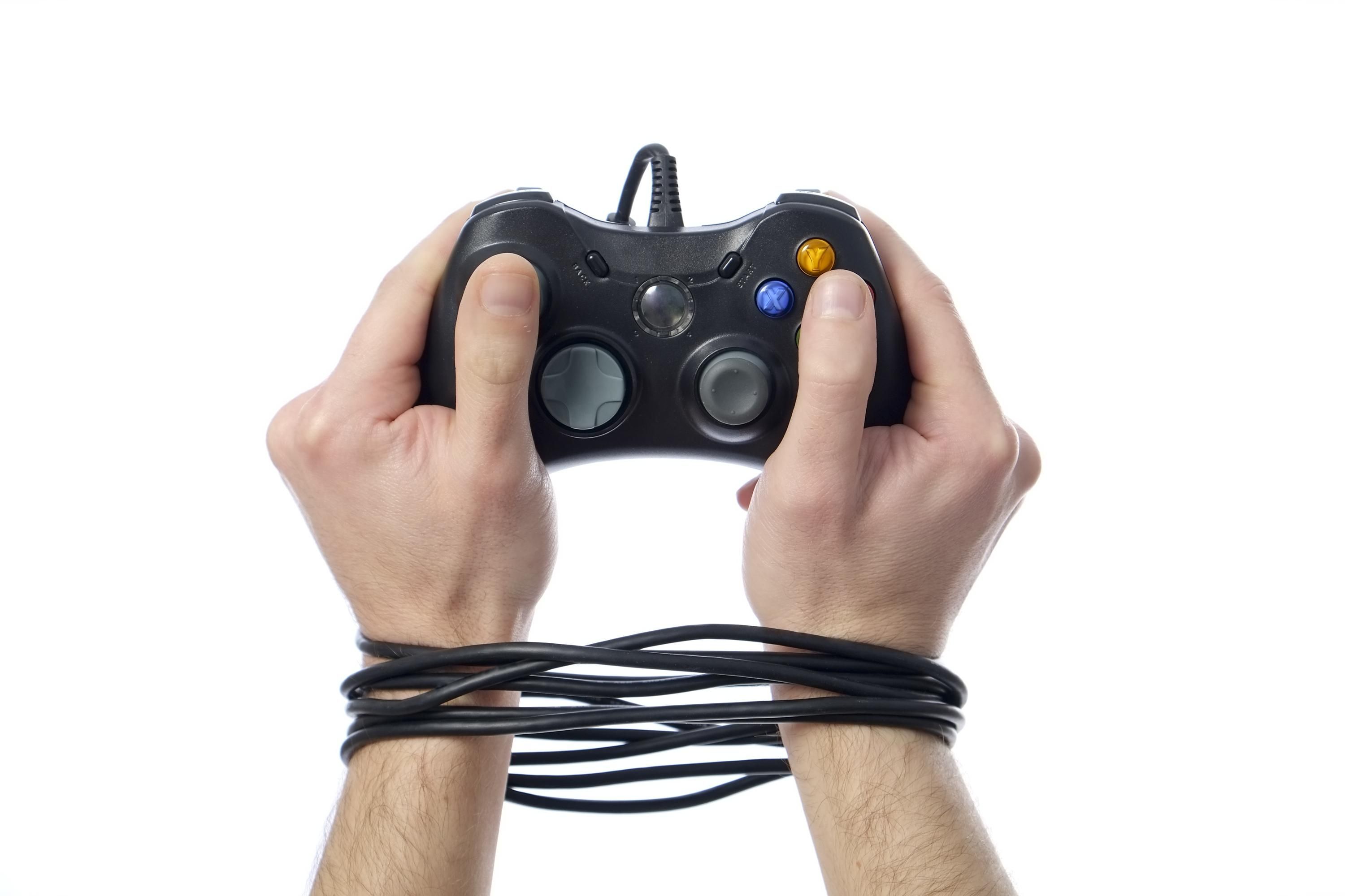 Béklyóba kötött, videojáték kontrollert tartó kezek