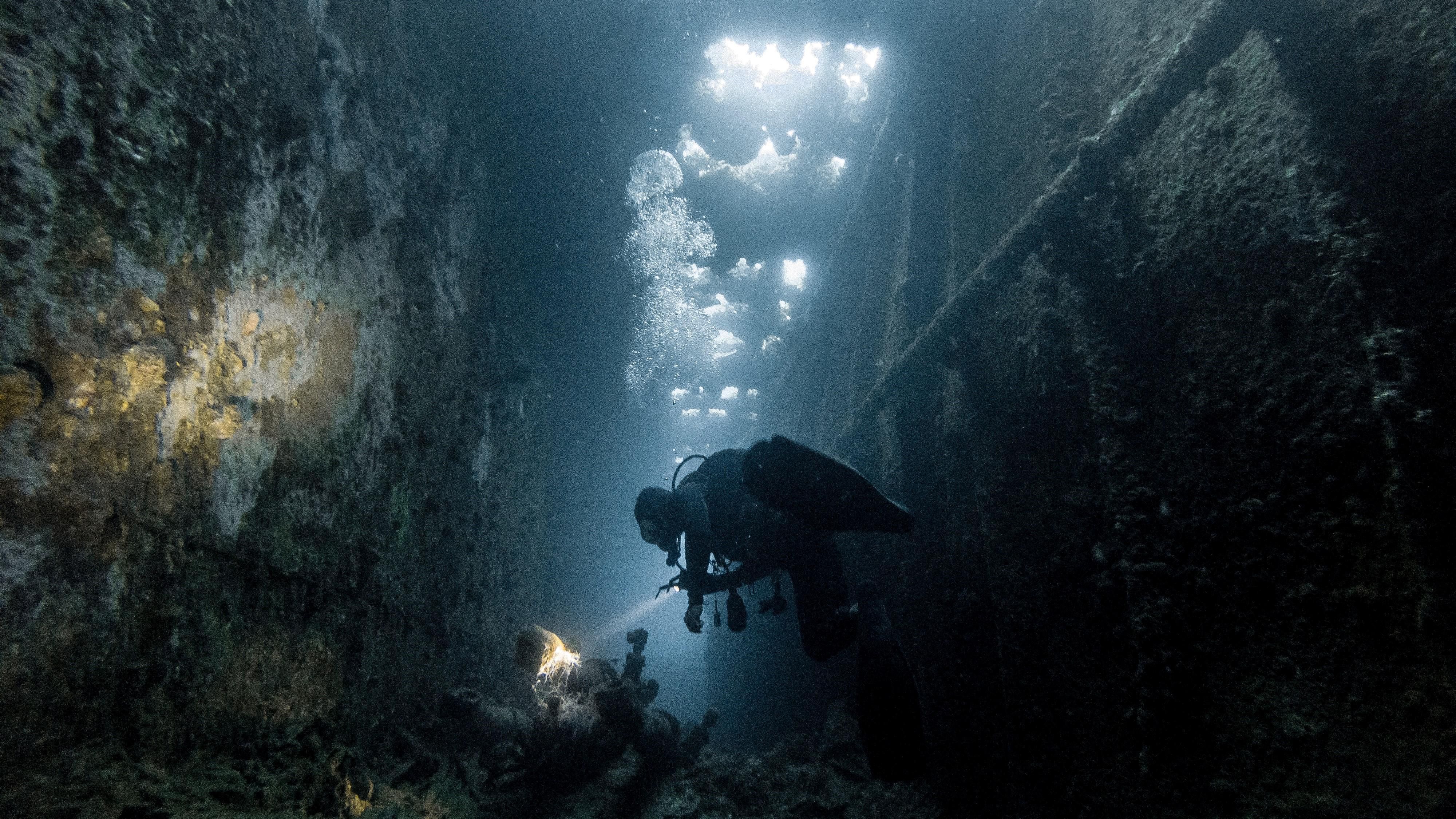Egy búvár zseblámpával kémleli a víz alatti talajt