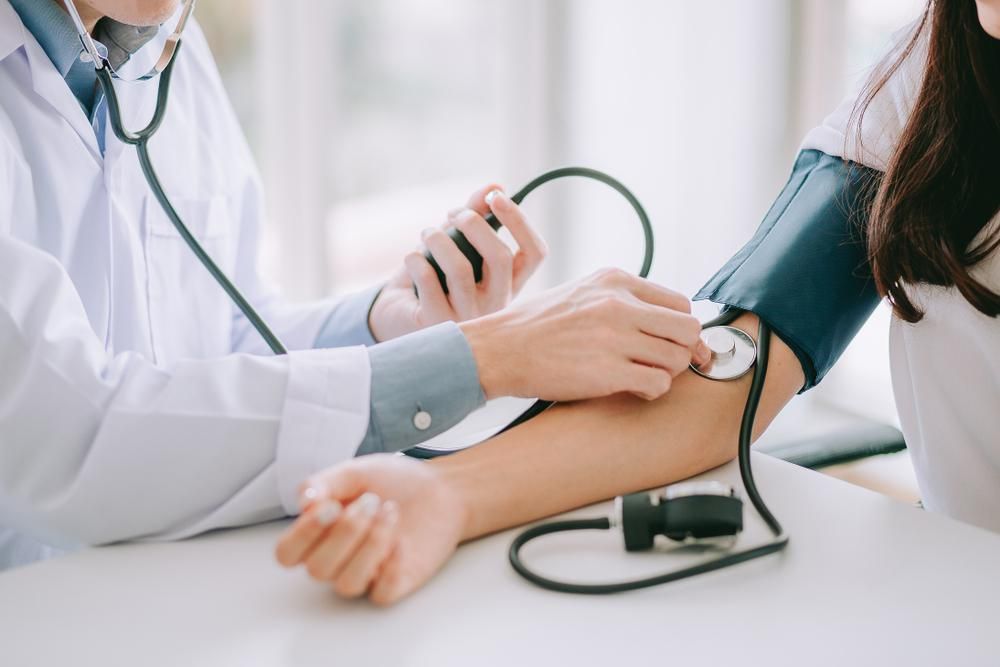 Orvos női beteg vérnyomását méri