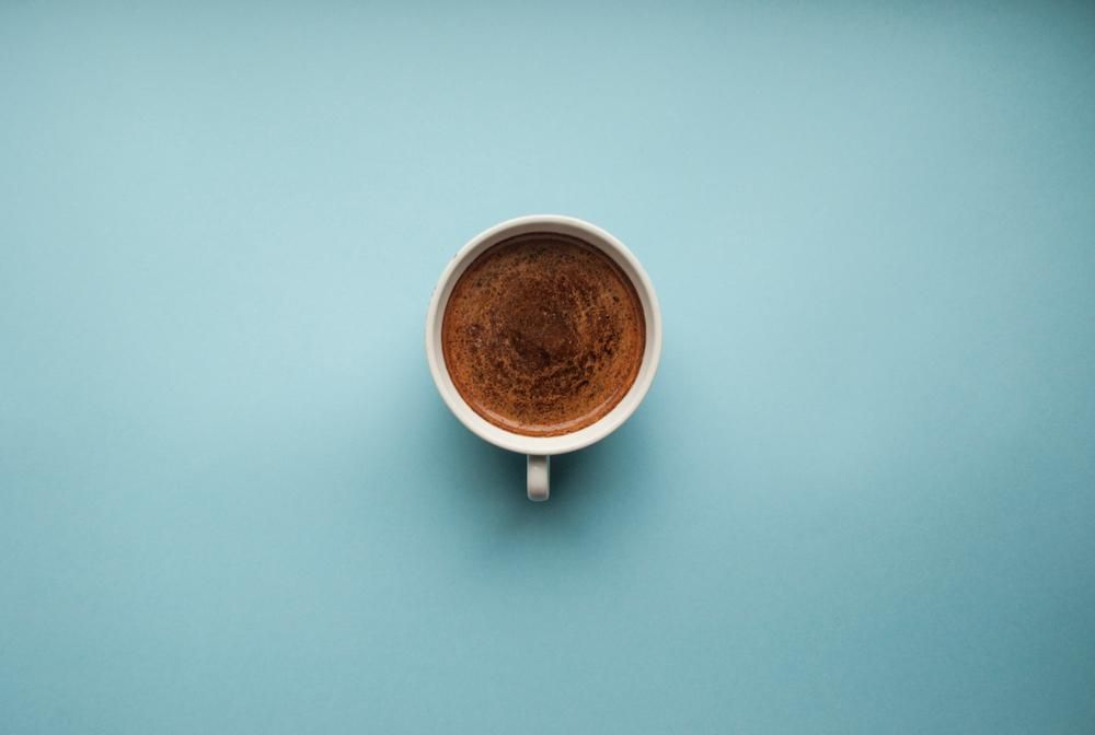 Egy csésze friss kávé, kék háttéren