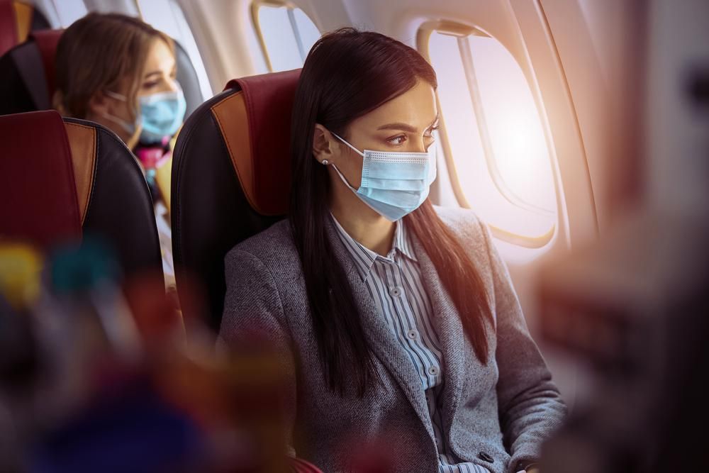 Repülőgépen ülő, maszkot viselő utasok