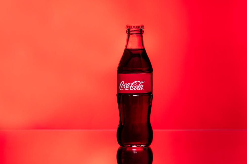 Coca-Cola ital üvegpalack piros színű háttér előtt