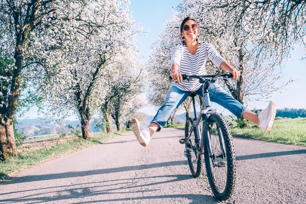 Boldog, mosolygó nő vidáman biciklizik az úton