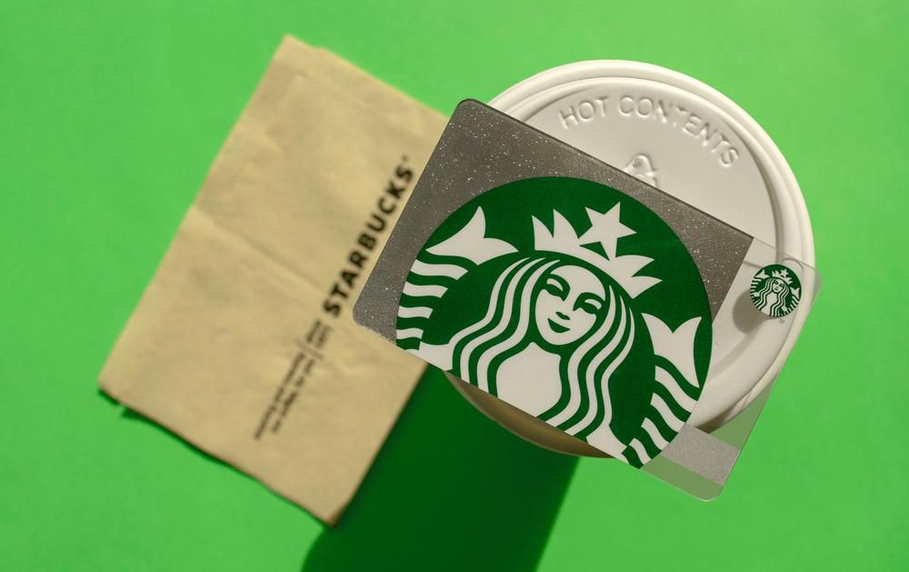 Starbucks ajándékkártya fehér elviteles poháron, szalvétával, zöld háttéren