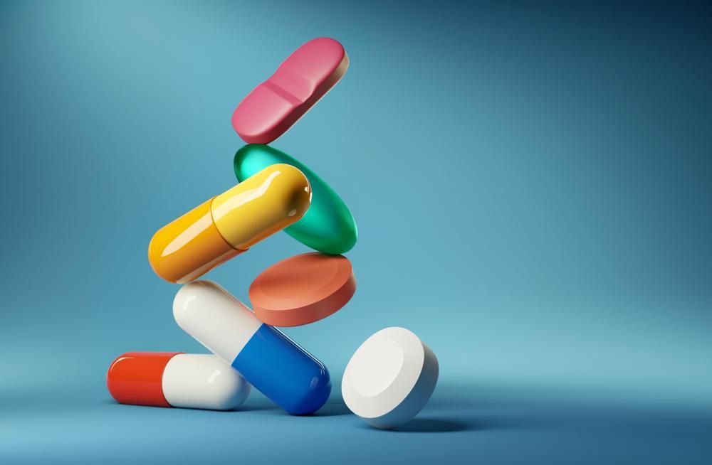 Gyógyszer tabletták és antibiotikumok egymás tetején, kék háttér előtt