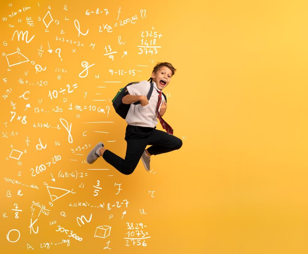 Fiatal fiú a levegőbe uhrik és "fut" a matematika elől, sárga háttér előtt