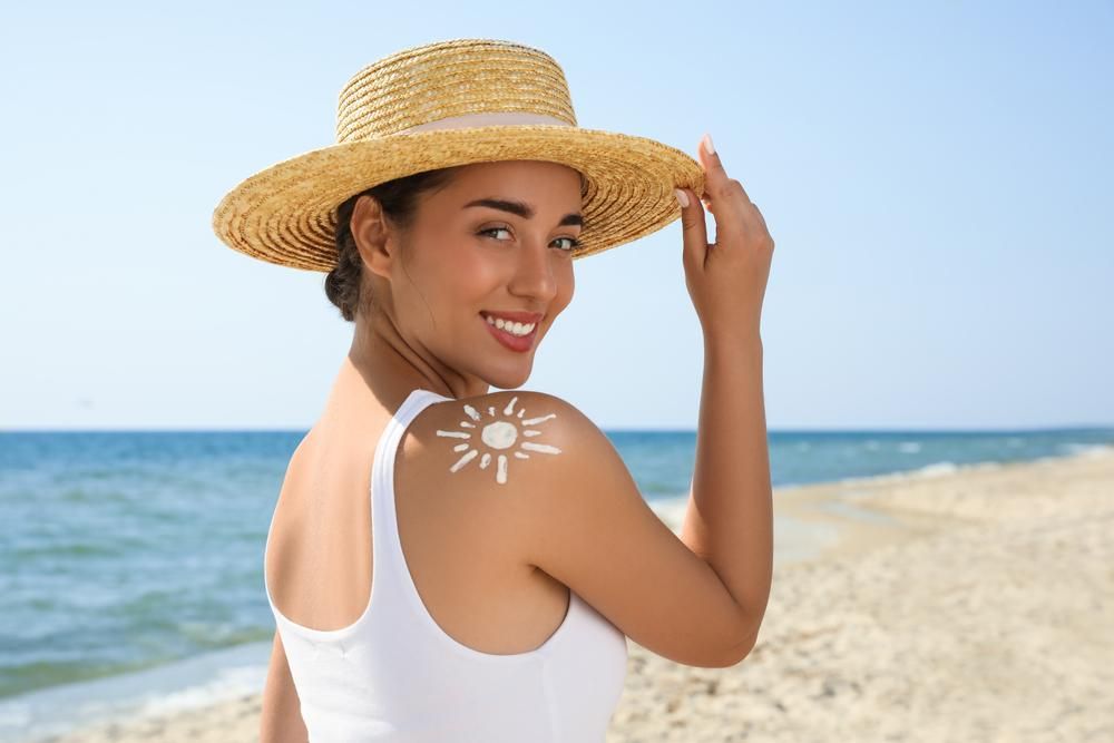 Fiatal nő napvédő krémmel a vállán a strandon