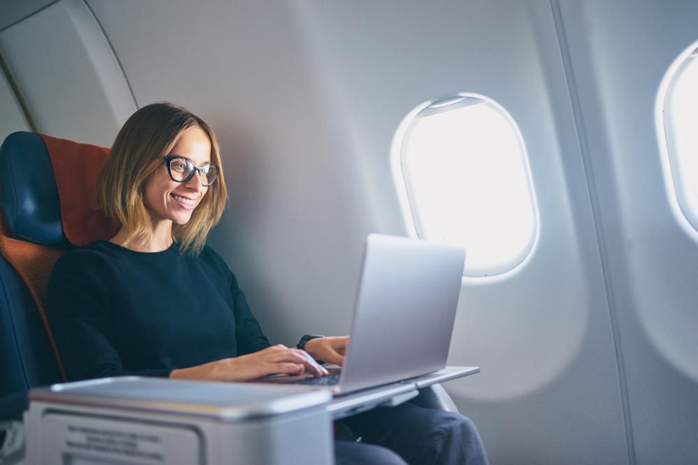 Fiatal nő laptopozik a repülőgépen