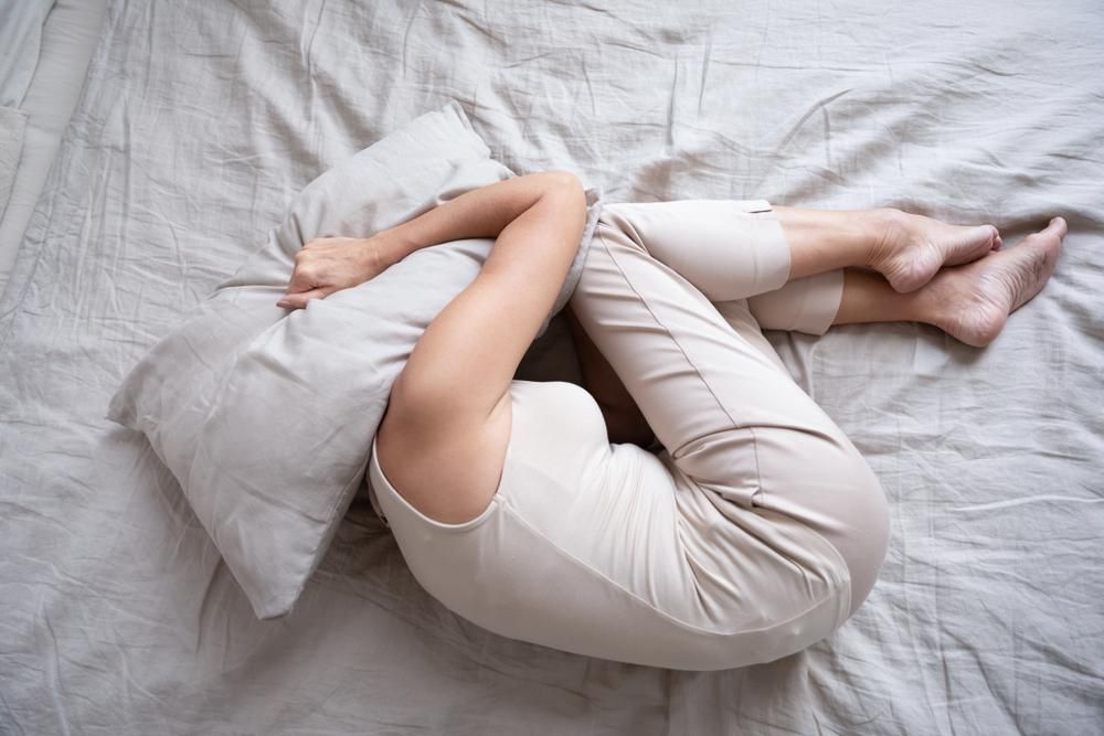Álmatlanságban szenvedő nő, párnát a fejére húzva fekszik az ágyon