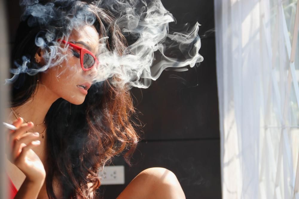 Fiatal nő dohányzik, füst lengi körül