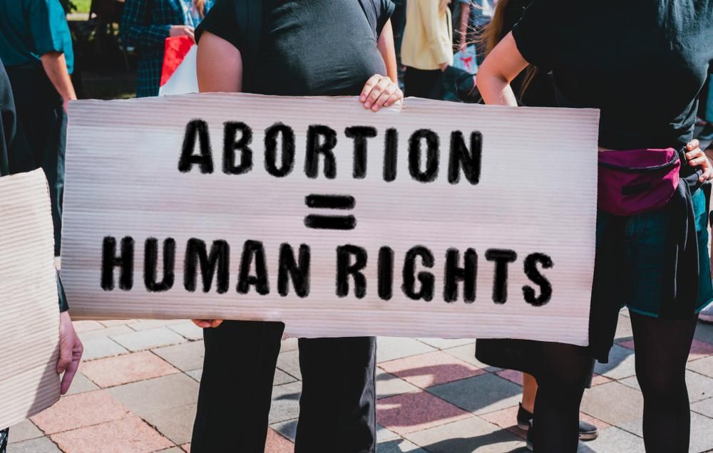 Az " Abortusz = emberi jogok " feliratú  transzparenss tartó női kéz. 