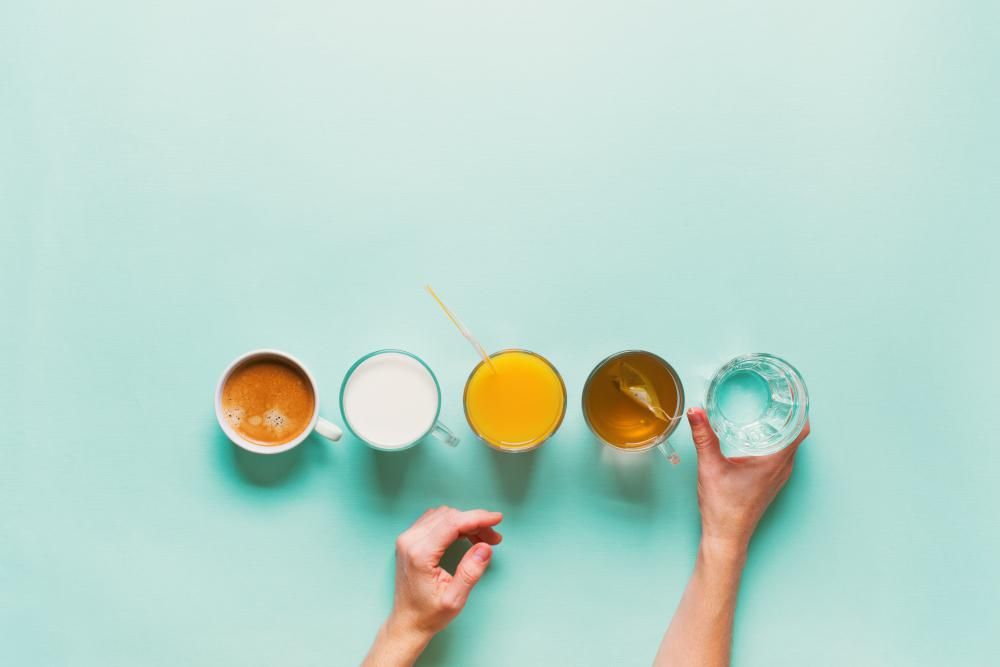 Különböző italok poharakban (kávé, tej, narancslé, tea, víz) kék háttéren