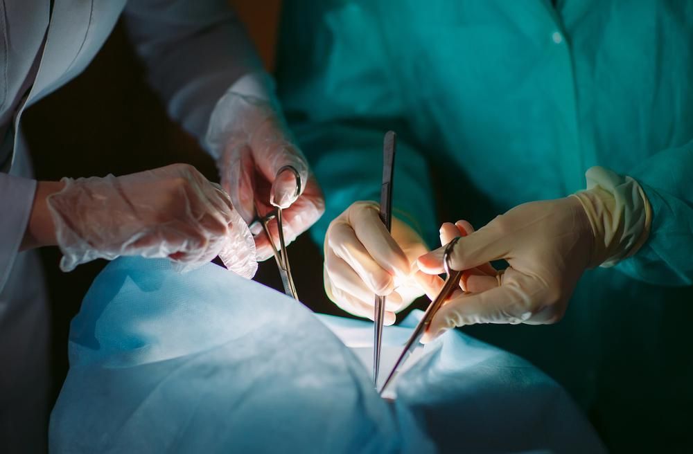 Sebészi beavatkozás egy páciensen, orvosi kezek műszerekkel
