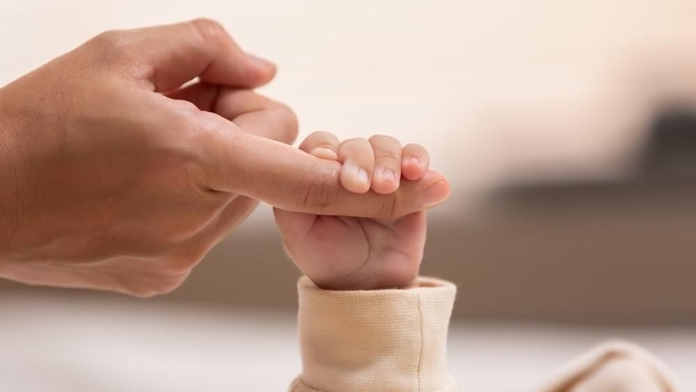 Egy kisbaba fogja az apukája ujját