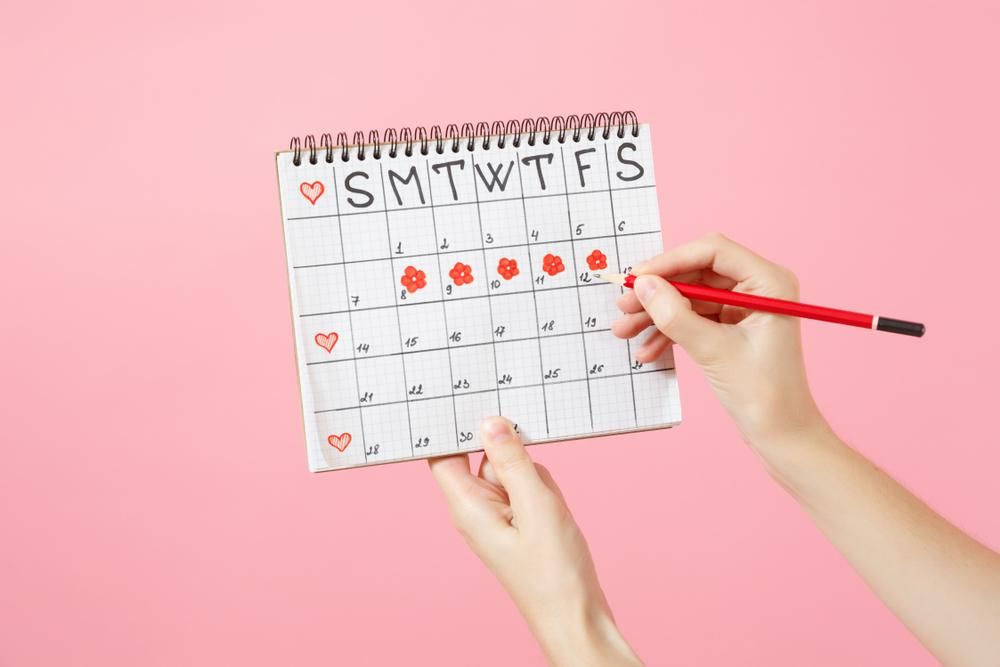 A naptárban a menstruációs időszakot piros virággal jelölő női kéz