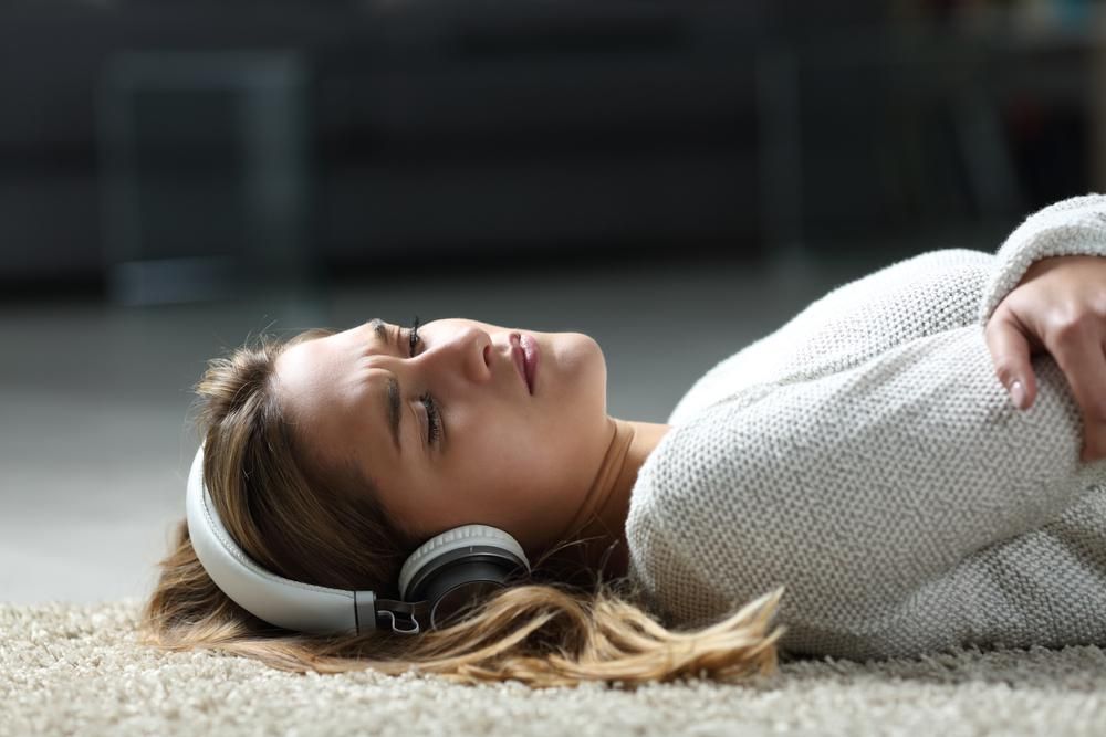 Szomorú nő zenét hallgat a padlón fekve
