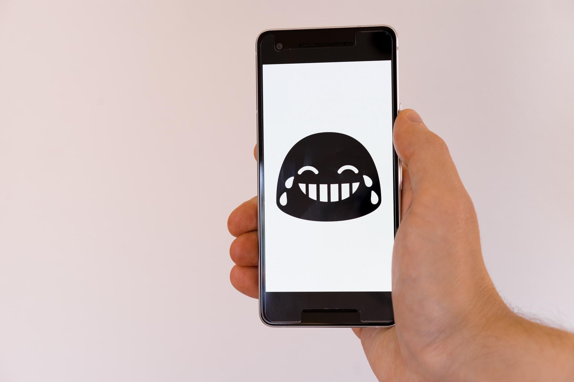 Sírva nevető emoji egy mobiltelefon képernyőjén