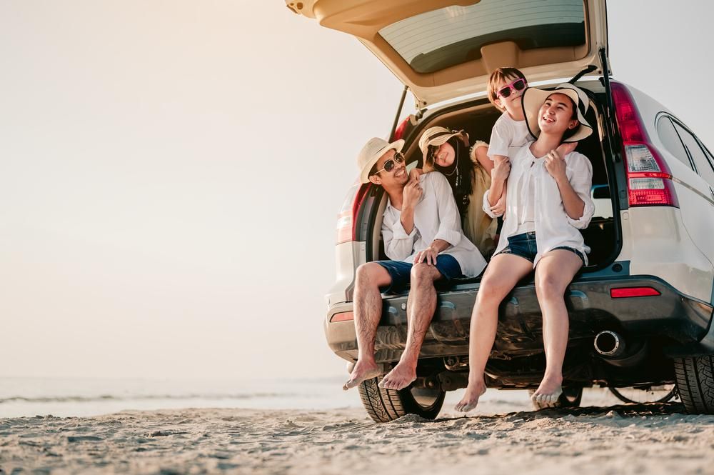 Boldog család a tengerparton a kocsi csomagtartójában ül