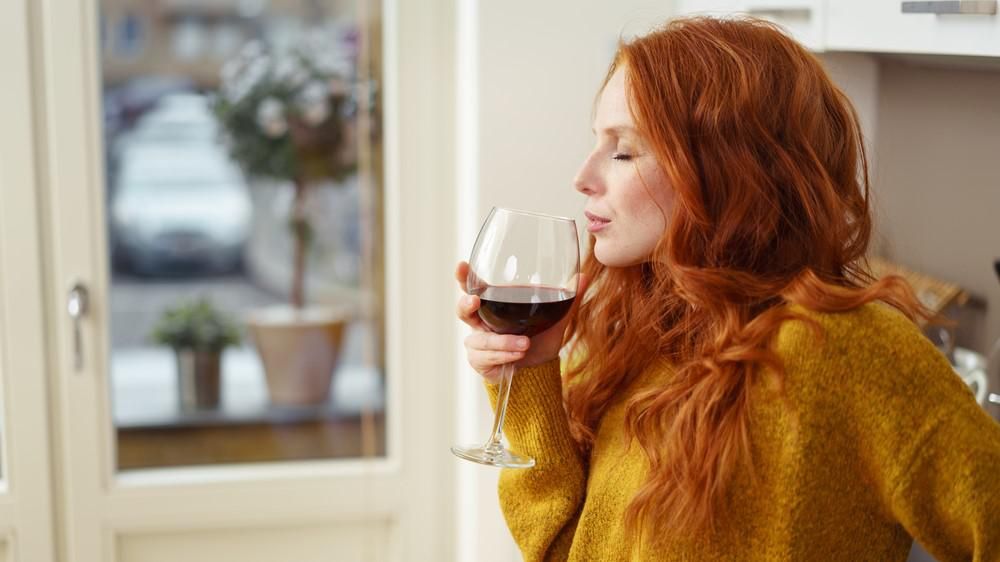 Egy sárga pulcsis nő vörösbort iszik
