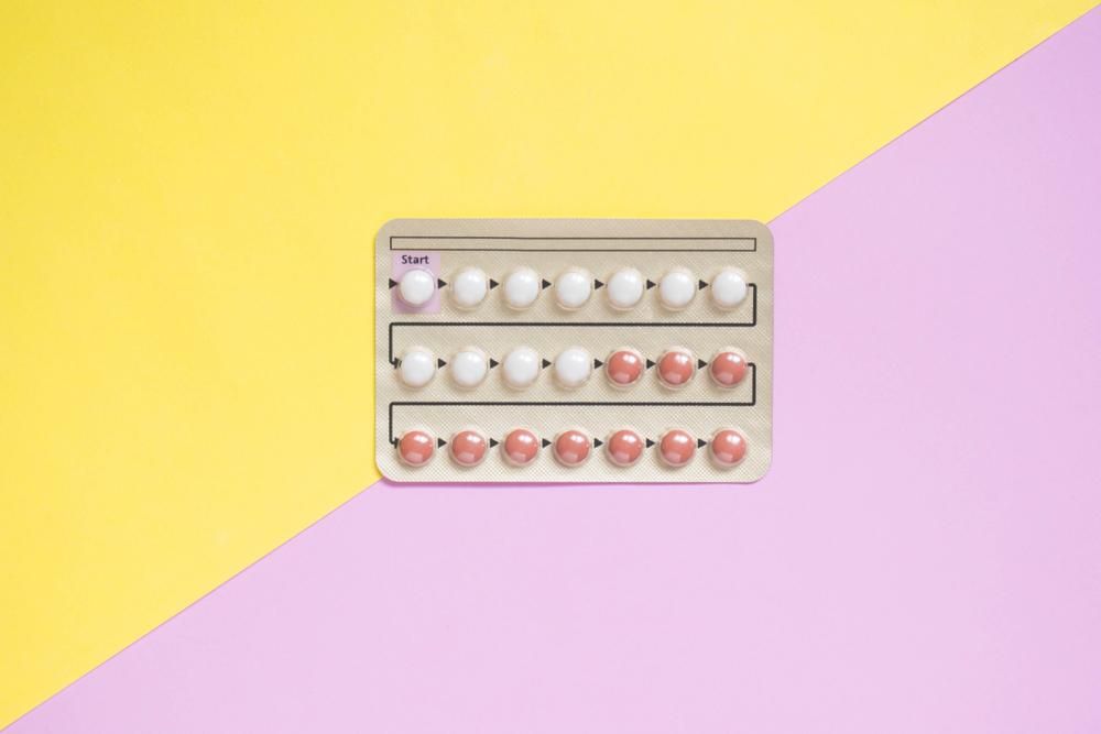   Szájon át szedhető fogamzásgátló tabletta, sárga rózsaszín háttéren