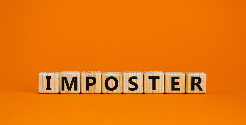 Fakockákon álló betűkből kirakott Imposztor(-szindróma) kifejezés narancssárga háttéren