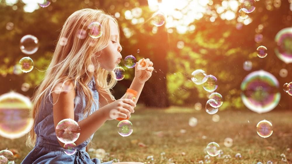 Egy szőke lány buborékfújóval játszik
