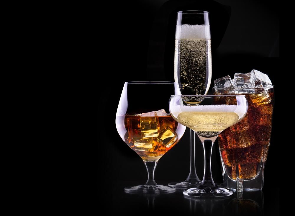 Különböző alkoholos italok fekete háttér előtt - pezsgő, konyak, bor, pálinka