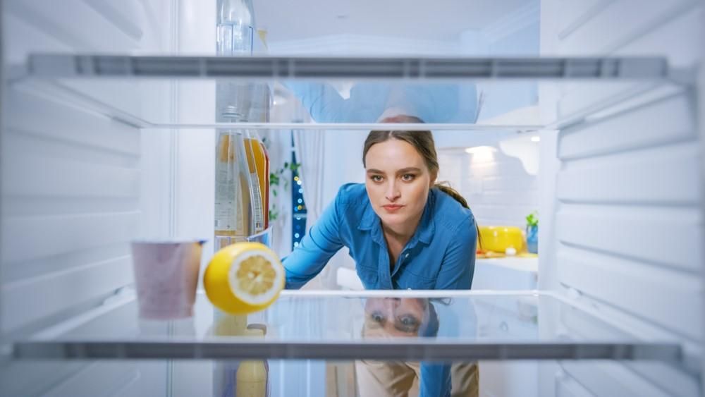 Egy nő kinyitja a majdnem üres hűtőszekrényét