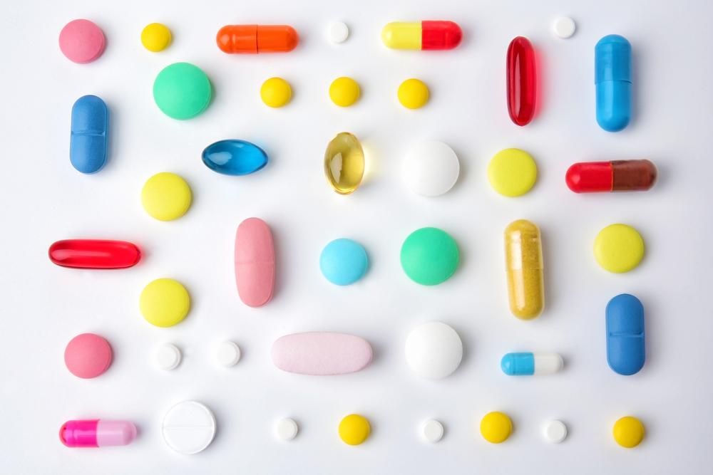 Különböző színes tabletták, fehér háttéren