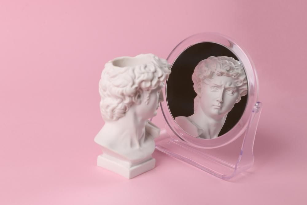 Dávid mellszobra csodálja magát a tükörben, rózsaszín háttér előtt